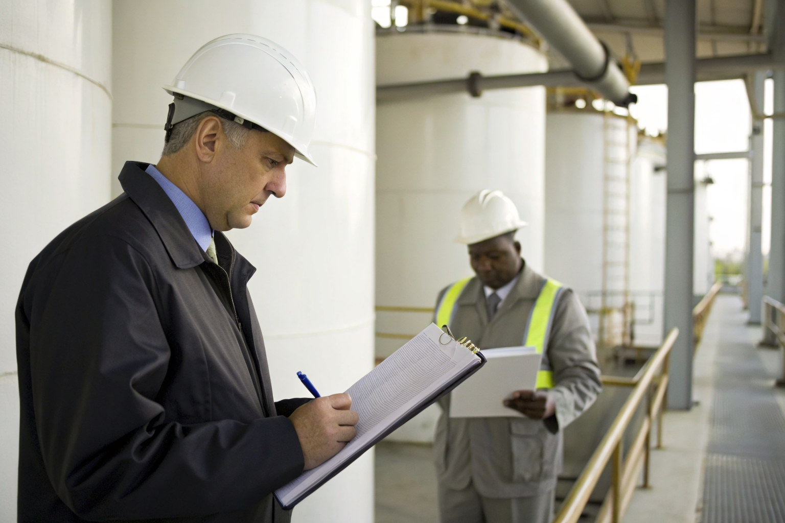 Inspector reviewing compliance documents at an oil facility.