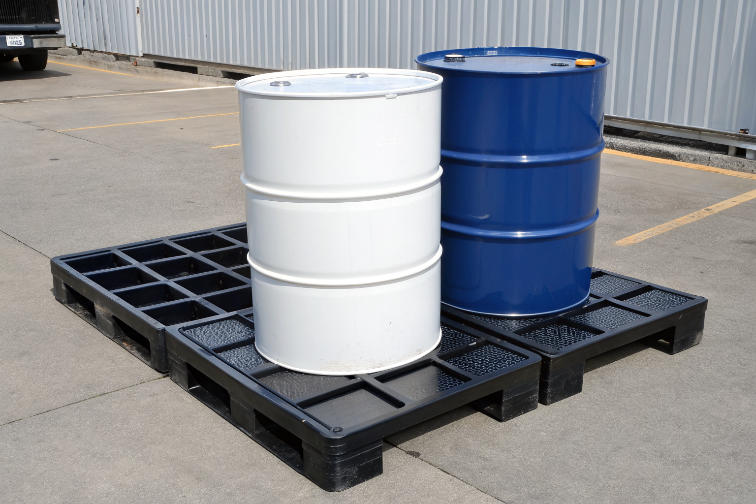 Drum drip pan next to full containment pallet showing capacity difference.