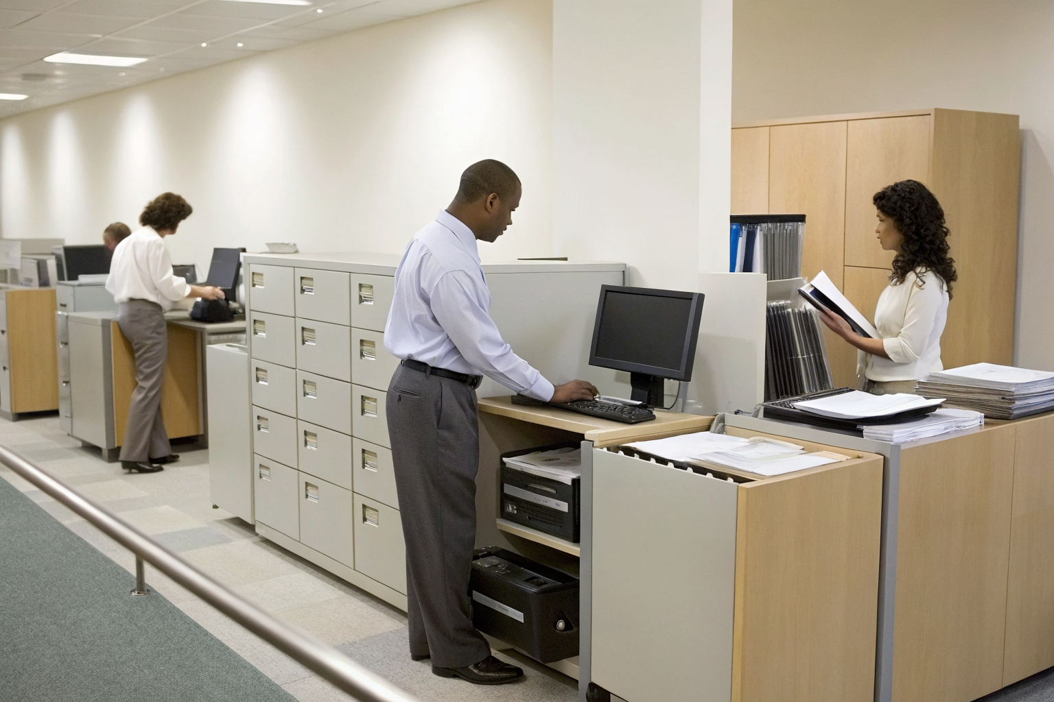 Office staff managing SPCC documentation with computers and records.