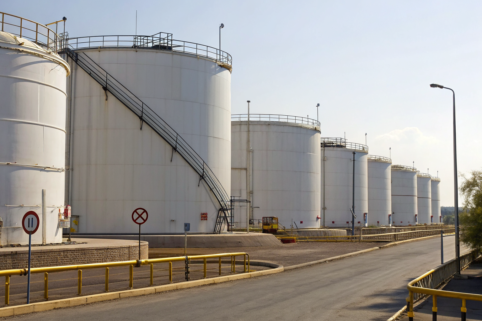 Oil storage facility with large tanks and safety signs.