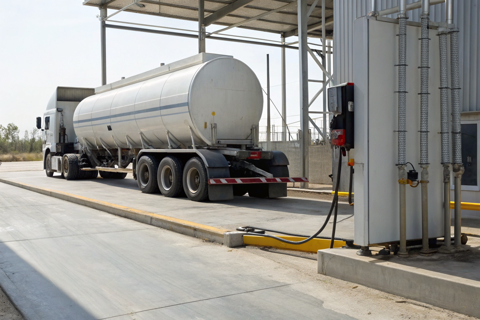 Tank truck with wheel chocks and electronic interlock display at a fuel transfer site.
